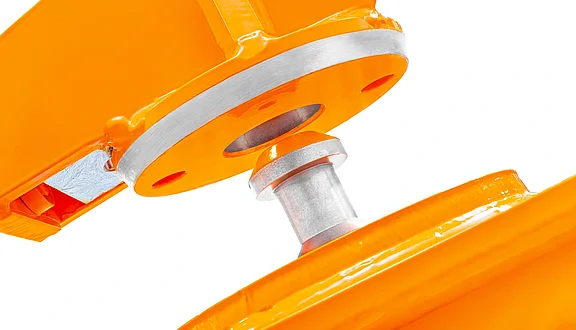 Nahaufnahme eines orangefarbenen mechanischen Teils, das eine Metallachse und eine silberne Lagerfläche zeigt. Der Fokus liegt auf der Verbindung zwischen zwei Bauelementen, die eine drehbare Bewegung ermöglichen.