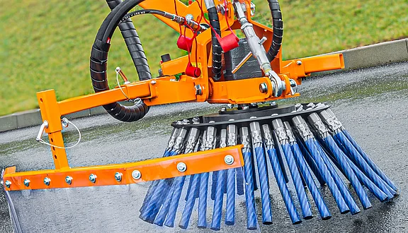 Eine Wildkrautbürste zur Beseitigung von Unkraut oder Wildkraut an Straßenrändern, auf Gehwegen und an Bordsteinkanten. Der Besen ist auf einer asphaltierenden Oberfläche positioniert und zeigt die Technik der Straßenreinigung an einem Frontausleger.