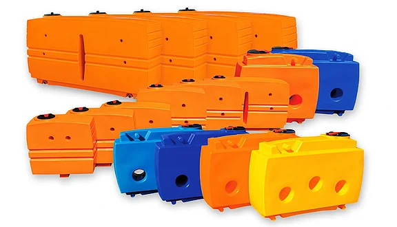 Das Bild zeigt eine Sammlung von Kunststofftanks in verschiedenen Farben, darunter Orange, Blau und Gelb. Die Behälter haben unterschiedliche Formen und Größen und sind für den Transport von Wasser gebaut.