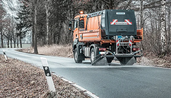 MAN LKW im Winterdienst mit Fiedler Solesprühanlage: Professionelle Glatteisbekämpfung durch Soleausbringung auf gefrorener Fahrbahn zur Gewährleistung der Verkehrssicherheit.